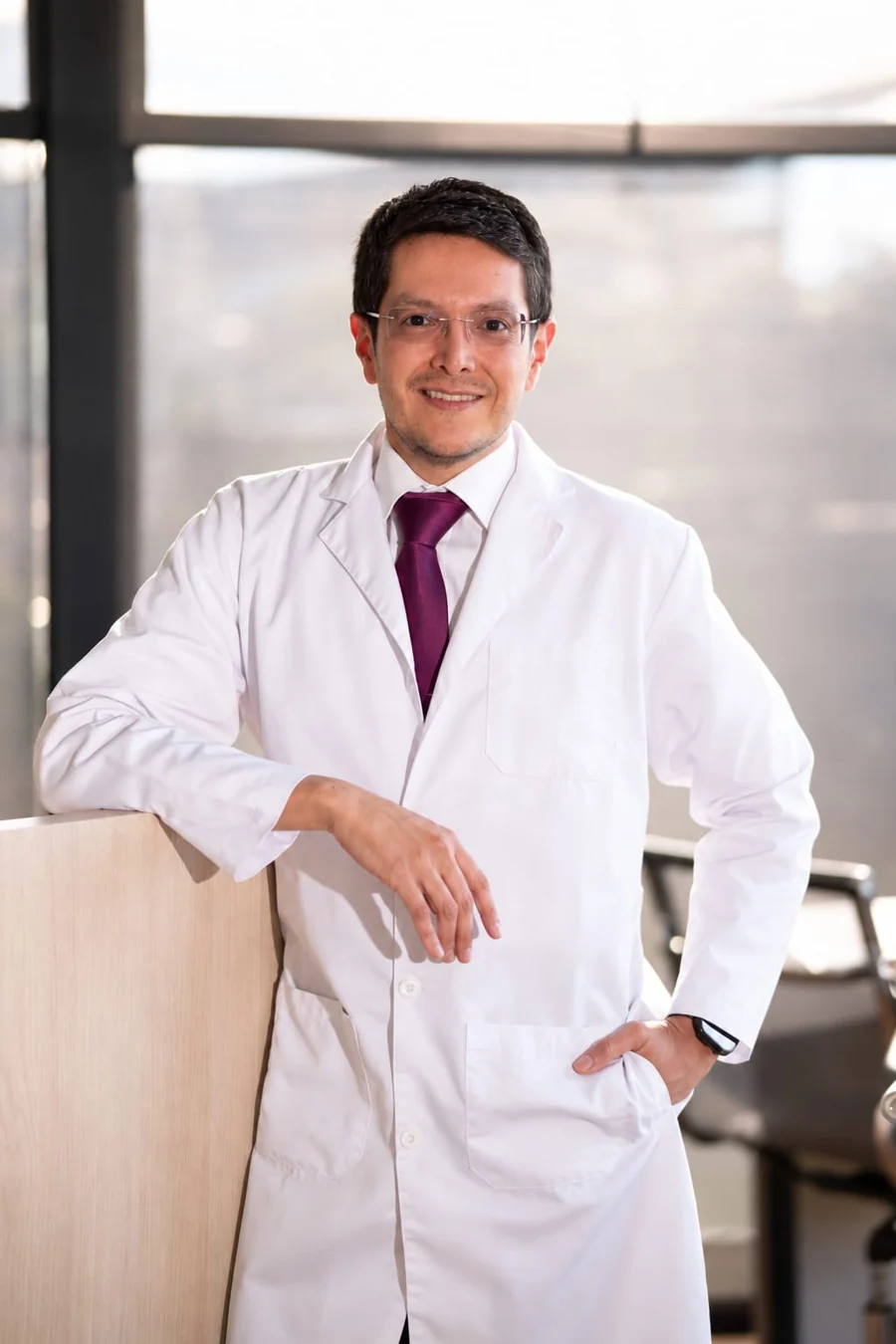 Dr. Juan David Linares con bata en su consultorio